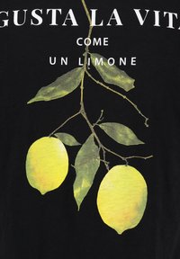Twee gele citroenen met groene bladeren die aan een tak hangen op een zwarte achtergrond met Italiaanse tekst.