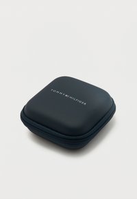 Συμπαγής θήκη σε σκούρο μπλε χρώμα με τετράγωνο σχήμα, φερμουάρ και στρογγυλεμένες γωνίες, με το λογότυπο Tommy Hilfiger στην κορυφή.