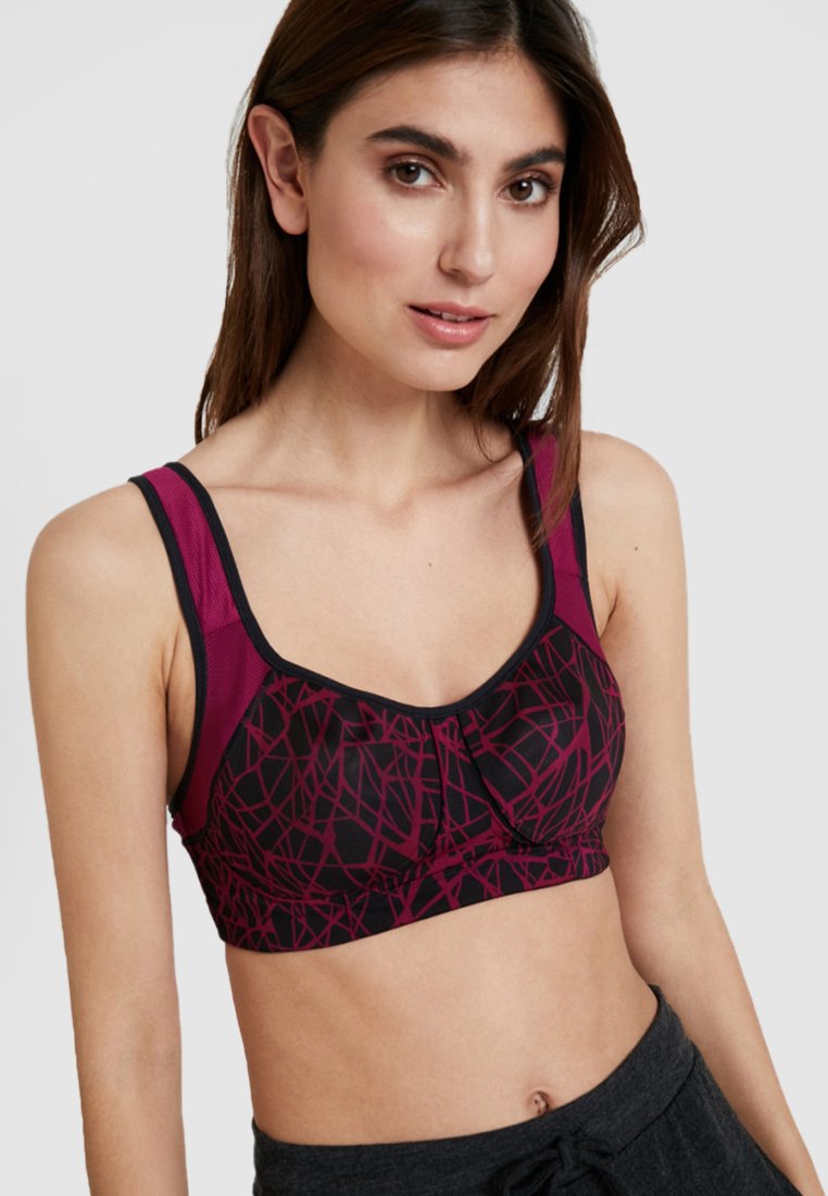 Soutien-gorge de sport noir et rose foncé avec un motif géométrique, des bretelles réglables et un tissu doux. Présente un détail subtil en forme de nœud au centre.