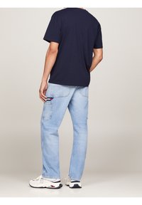 Námořnické bavlněné tričko spojené se světle modrými džínami s kapsami na cargo. Modelka má na sobě bílé tenisky s námořnickými a červenými detaily.