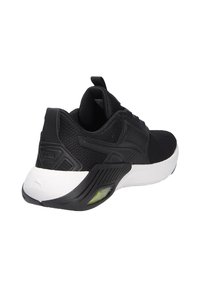 Schwarzer Sportschuh mit Obermaterial aus Mesh, gepolstertem Kragen und weißer Sohle. Verfügt über strukturierte Überzüge und grüne transparente Details an der Ferse.