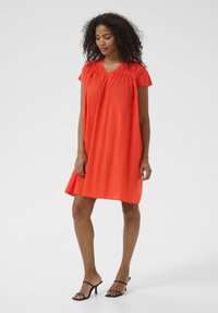 Oranges Baumwollkleid mit V-Ausschnitt, kurzen Ärmeln und gerafftem Detail am Ausschnitt. Lockere Passform, bis zur Mitte des Oberschenkels reichend, mit glatter Textur.