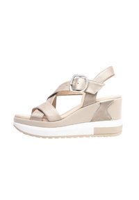 Beige wedge sandals with cross strap design, featuring a metallic buckle and textured fabric accents on the heel. White rubber sole.