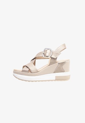 Beige Keilsandalen mit einem Kreuzriemen-Design, ausgestattet mit einer metallischen Schnalle und strukturierten Stoffakzenten an der Ferse. Weiße Gummisohle.