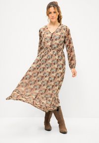 Maxikleid aus leichtem Stoff mit einem mehrfarbigen Blumenmuster. Mit V-Ausschnitt, Knöpfen und langen Ärmeln. Braune Ankle Boots.