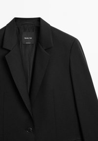 Zwarte op maat gemaakte blazer met ingesneden revers en sluiting met één knoop, met het label Massimo Dutti, getoond tegen een witte achtergrond.