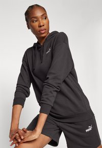Zwarte hoodie met een trekkoord, ribbelmanchetten en het Puma-logo. Draagbare combinatie met bijpassende zwarte shorts, voorzien van logodetails. Zacht, textuurstof.
