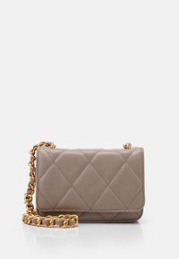 Piccola borsa a tracolla in pelle trapuntata taupe con chiusura a soffietto e tracolla in metallo dorato, appoggiata su una superficie bianca.
