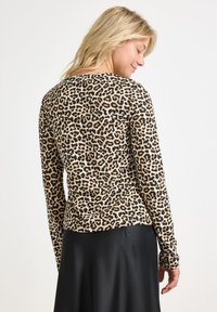 Långärmad topp i lätt tyg med ett leopardmönster i beige och svart. Rundad hals och figurnära design.
