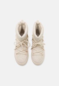 Bottines beige à tige en feutre et semelle en caoutchouc, avec des lacets à accents métalliques et un revers pour plus de chaleur.