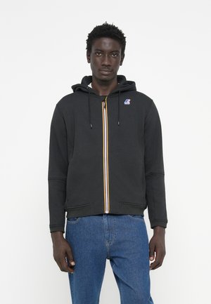 Felpa nera con zip e cappuccio regolabile, caratterizzata da una striscia colorata lungo la zip e un piccolo logo sul petto. Tessuto morbido, vestibilità rilassata.