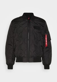 Mustat pommikopiotakki, jossa on tikkikuvio, ribbikaulus ja hihansuut, etuvetoketju ja sivutasku. Mukana punainen tarra, jossa on tekstitietoja.