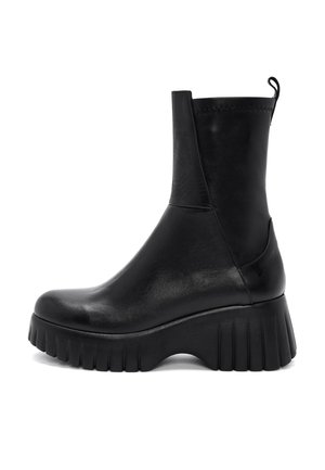 Bota negra de cuero hasta media pantorrilla con suela gruesa estriada y pestaña para tirar en la parte trasera, mostrada de perfil sobre fondo blanco.