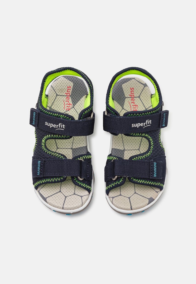 Marineblaue Sandalen mit zwei verstellbaren Riemen, ausgestattet mit einer perforierten grauen Innensohle und leuchtend grünen Akzenten. Strukturierter Gummiaußensohle.