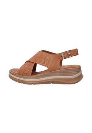 Tan platform sandal made of textured synthetic material, featuring crisscross straps, a back buckle, and a cushioned sole with a slight wedge.