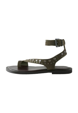Sandale thong verzi din suede, cu o curea cu cataramă, cu nite metalice pe partea superioară și o talpă plată de un maron închis.