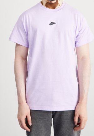 T-shirt di cotone lilla con collo rotondo e maniche corte, caratterizzata da un piccolo logo Nike nero sul petto. Tessuto liscio, vestibilità casual.