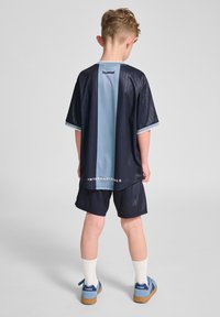 Marinblå och ljusblå sportdräkt med randigt mönster, korta ärmar och matchande shorts. Texten "INTERNATIONALS" är synlig på baksidan.