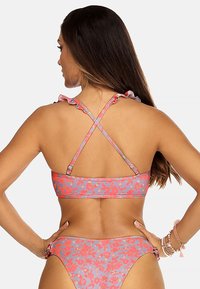 Zestaw bikini w kwiatowy wzór w odcieniach różu i niebieskiego, z falbanami na ramiączkach i krzyżującym się tyłem. Gładka tekstura i regulowane dopasowanie.