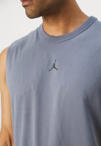 Canottiera grigia in cotone senza maniche con un discreto logo Jumpman nero sul petto. Texture liscia con scollatura rotonda.