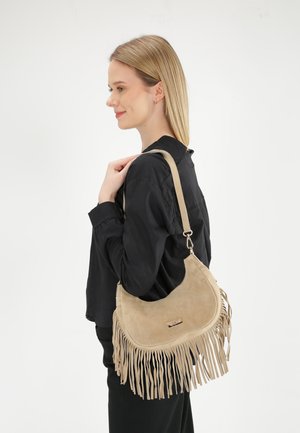 Beige Wildleder-Schultertasche mit Fransen-Details, runder Form und einem langen Tragegurt. Goldfarbene Hardware-Akzente verleihen dem Design eine zusätzliche Note.