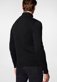 Czarny dzianinowy sweter z wysokim kołnierzem, prążkowanymi mankietami i dołem. Tekstura jest gładka, a krój dopasowany do ciała.