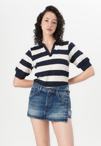 Marineblå og hvite stripete polo skjorte med V-hals og korte puff ermer, kombinert med en denim mini skjørt med frontlommer og knapp detaljer.