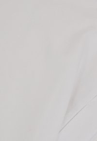 Tessuto bianco semplice con un piccolo angolo piegato sul lato destro su sfondo bianco.