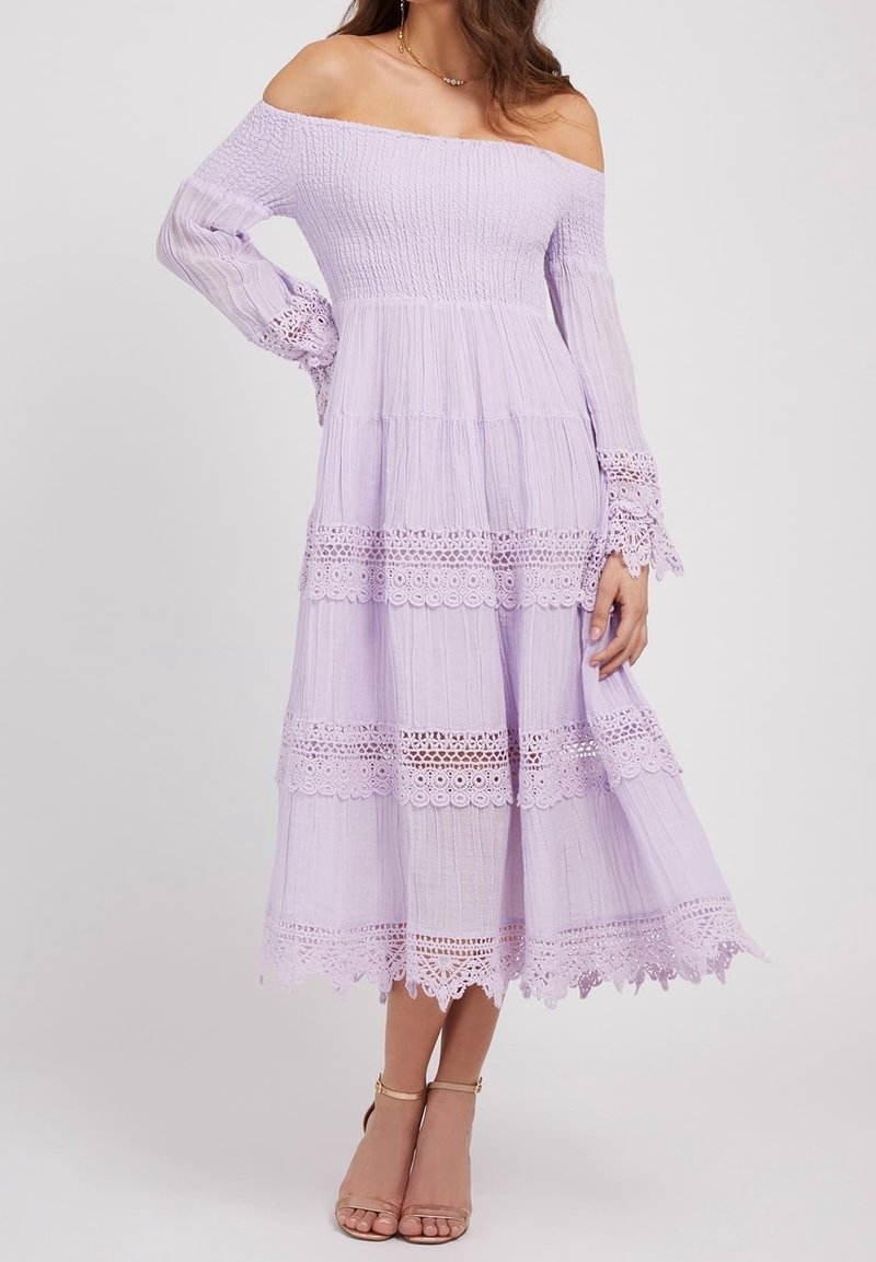 Lavendel Kleid mit schulterfreiem Design, das einen gerafften Mieder und lange Ärmel mit Spitzenakzenten aufweist. Stufen-Design mit Broderie anglaise Detail am Saum.