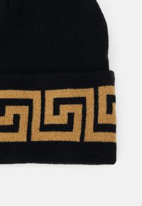 Black knitted beanie with a gold and black geometric pattern along the brim, featuring a soft texture and fitted design.
