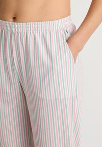 Gestreepte pyjamabroek met een elastische tailleband. Bevat afwisselend roze en groene verticale strepen, en zijzakken. Zacht katoenen stof.