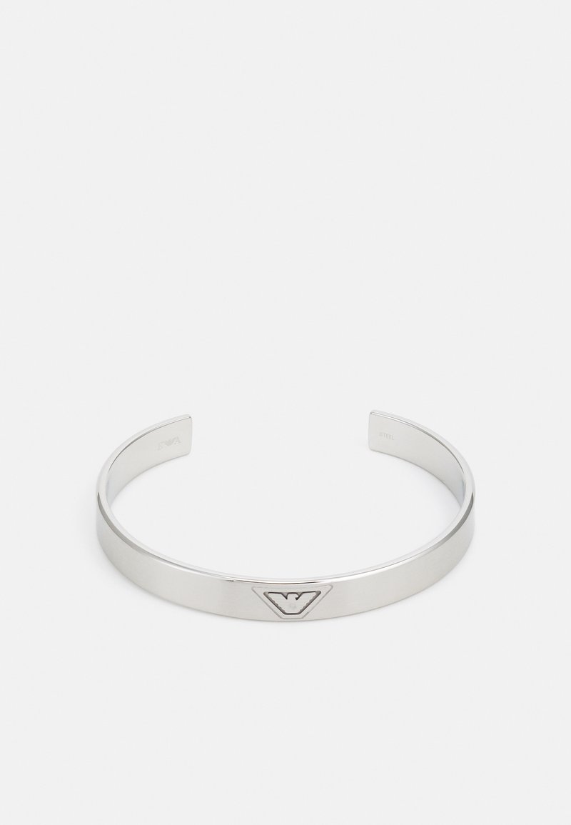 Stříbrný kovový náramek s hladkým povrchem, ve středu s trojúhelníkovým logem. Otevřené konce pro nastavitelnou velikost.