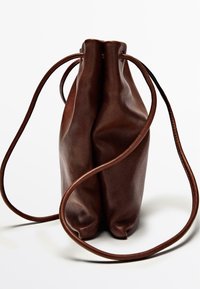 Borsa a sacco in pelle marrone con una texture liscia, forma arrotondata e sottili e lunghe cinghie che pendono dalla parte superiore.