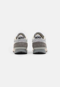 Grå og beige sneakers med overdel i semsket skinn og lær, med en polstret såle, polstret krage og "ROOS"-logo på hælen.