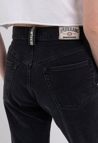 Svarta jeans med hög midja, med fem fickor, ett märkespatch på baksidan av midjebandet och en kontrasterande logotagg.