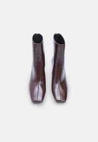 Brown leather ankle boots with a square toe design, featuring a smooth texture and side zippers for easy wear.