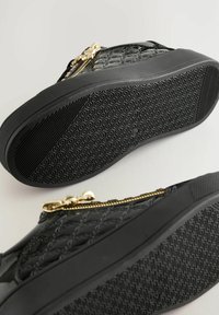 Schwarze lackledersneaker mit strukturiertem, gestepptem Muster und goldenen Reißverschlussdetails; Gummisohle mit sechseckigem Profil.
