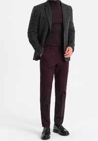 Ciemnoszara marynarka o fakturze na bordowym golfie, do tego dopasowane bordowe spodnie i czarne eleganckie buty.