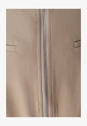 Gai brūns džemperis ar priekšu esošu metāla rāvējslēdzēju, divām vertikālām kabatām un gludu tekstūru. Minimalistisks dizains ar tīrām līnijām.