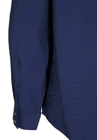 Camicia blu navy con superficie texture, dotata di orlo curvo e polsini con bottoni. Realizzata in tessuto leggero.