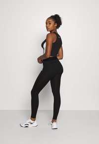 Czarny i biały krótki top sportowy w połączeniu z czarnymi legginsami z wysokim stanem i białymi sneakersami, charakteryzujący się dopasowanym krojem i gładką teksturą.