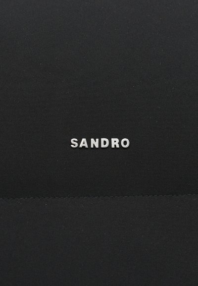Zwarte stof met een gladde textuur met in het midden de verhoogde zilveren tekst "SANDRO". Eenvoudig en minimalistisch ontwerp.
