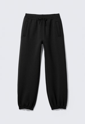 Pantalon de jogging noir avec poignets élastiques, taille à cordon et deux poches latérales, posé à plat sur un fond clair.