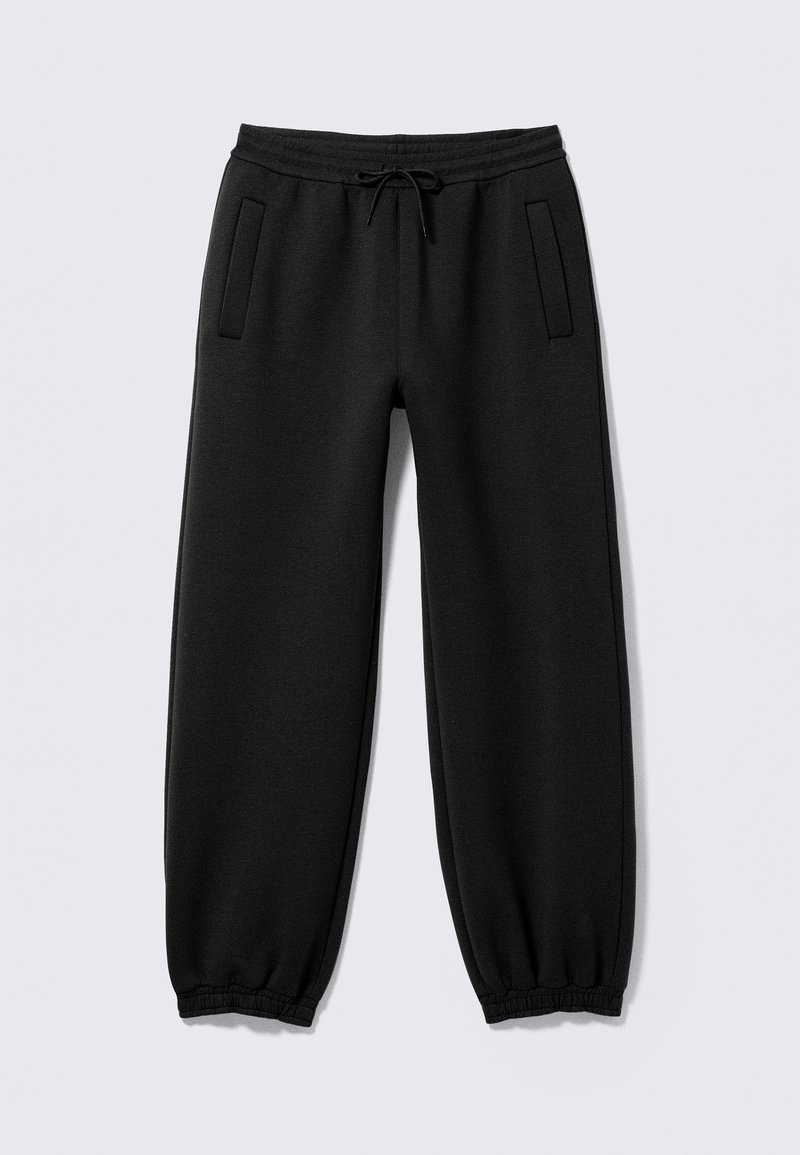 Pantalon de jogging noir avec poignets élastiques, taille à cordon et deux poches latérales, posé à plat sur un fond clair.