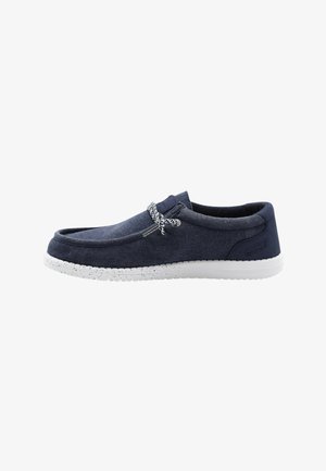 Chaussure décontractée bleu marine à enfiler avec semelle blanche tachetée et lacets à motif noir et blanc.