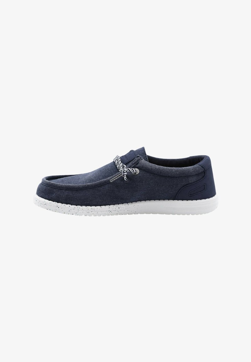 Chaussure décontractée bleu marine à enfiler avec semelle blanche tachetée et lacets à motif noir et blanc.