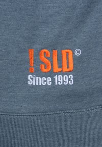 Sudadera gris con texto bordado en naranja "!SLD" y "Desde 1993" en blanco, con un dobladillo acanalado y textura suave.