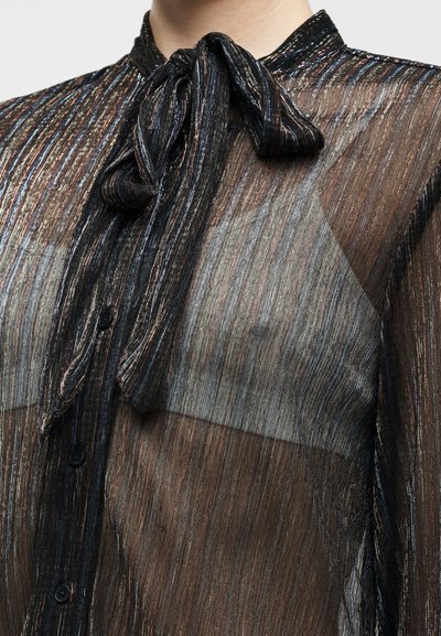 Črna prosojna bluza z nitmi v srebrni in bakreni kovinski barvi. Ima ovratnik z zavezovanjem, gumbe spredaj in teksturirano tkanino za eleganten videz.