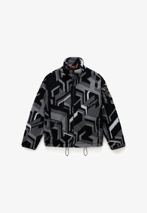 Veste en polaire noire et grise avec des motifs géométriques ; possède un col haut, une fermeture éclair, des poches latérales et des cordons de serrage ajustables.
