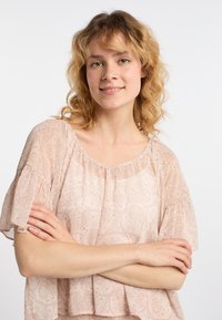 Blusa rosa chiaro con maniche corte a campana; presenta un motivo paisley e un colletto arruffato. Realizzata in un tessuto fluido e testurizzato.